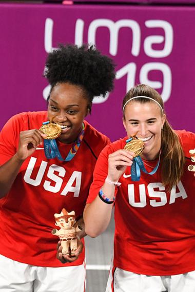 American basketball players Sabrina Ionescu, Olivia Nelson, Ruth Hebard and Christyn Williams bite their gold medals