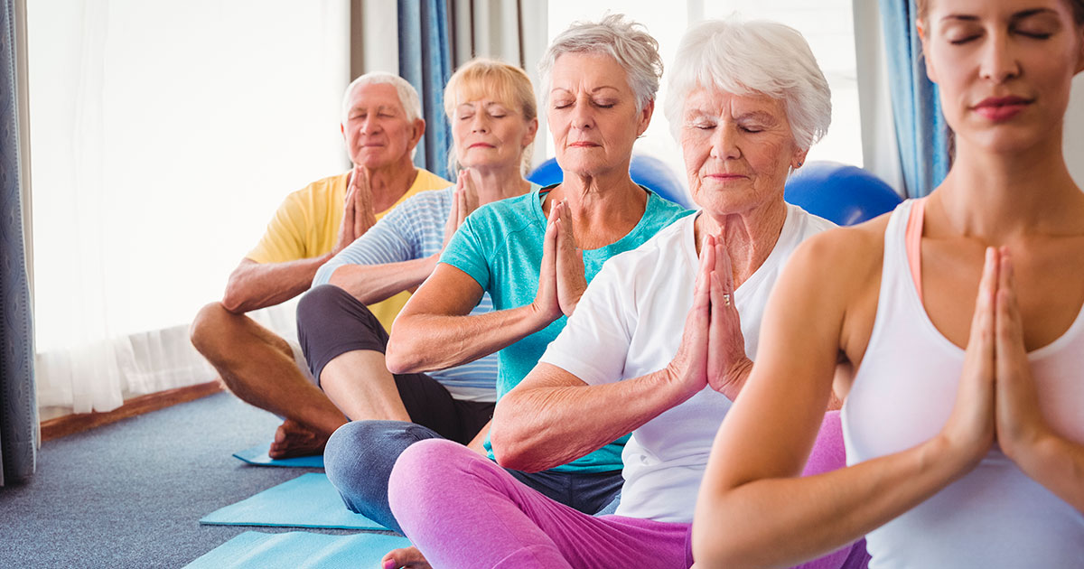 Adultos mayores realizan posturas de yoga