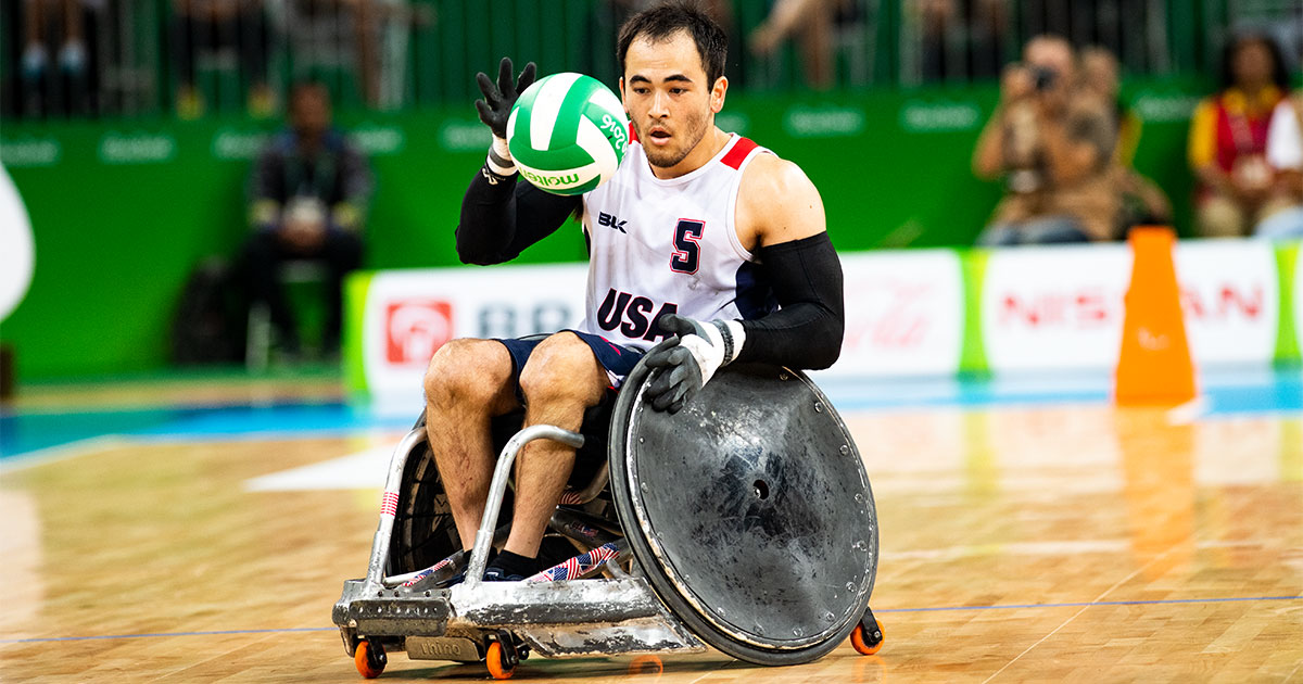 Jugador estadounidense de rugby en silla de ruedas atrapa balón durante partido