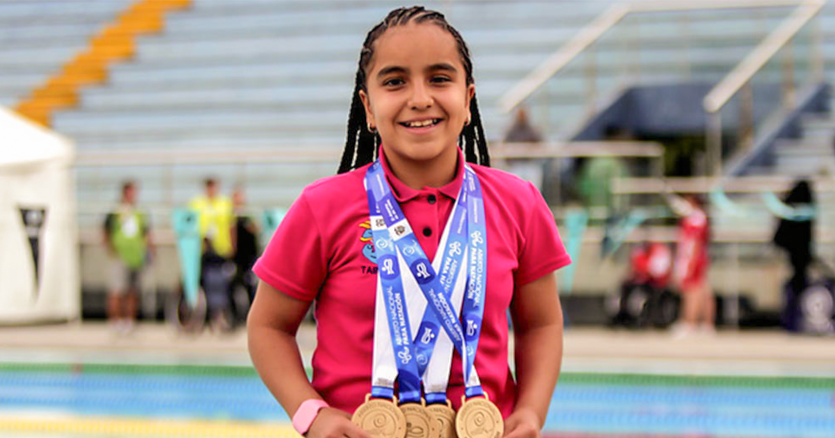 Sara Vargas sonríe a la cámara mientras sostiene sus medallas.