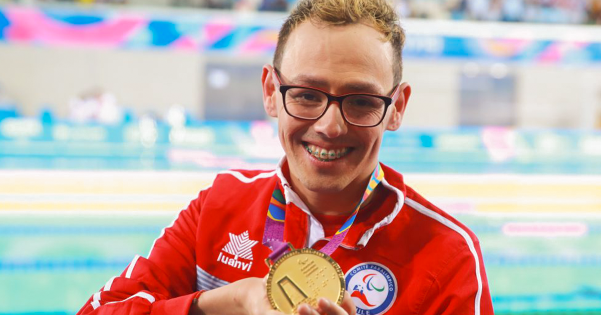 Alberto Abarza sonríe a la cámara mientras sostiene su medalla de oro parapanamericana Lima 2019. 