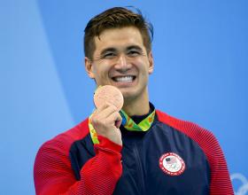 Nathan Adrian, nadador olímpico, celebra junto a su medalla. 