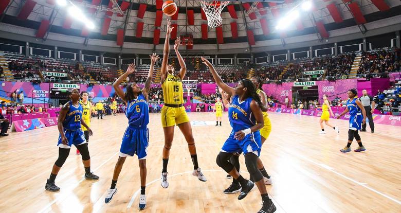 Colombian basketball player Narlyn Mosquera scores a basket vs. Anisha George and Kadesha Barry from Virgin Islands during the Lima 2019 Games at the Eduardo Dibós Coliseum