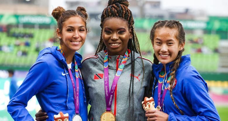 Beatriz Hatz (silver) and Catherine Carey (bronze) from the US, and Nyoshia Cain-Claxton from Trinidad and Tobago (gold) smile with their medals in the Lima 2019 women’s 100 m T64 competition at the National Sports Village - VIDENA