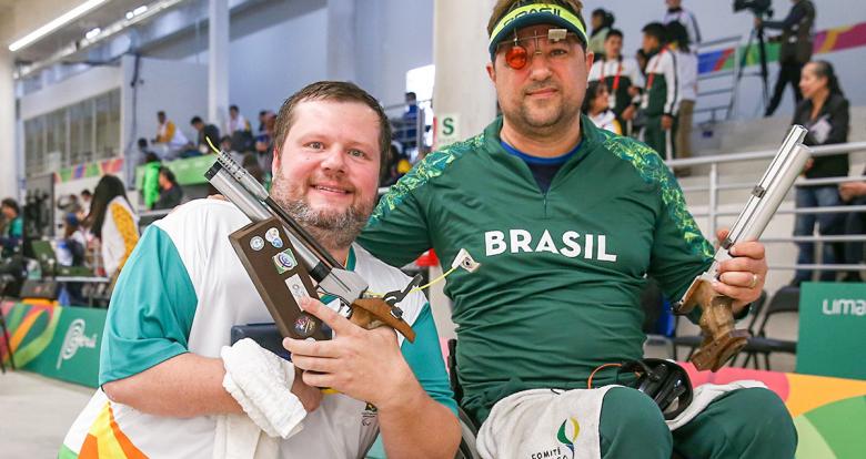 Geraldo Rosenthal and Adriano Sergio from Brazil pose proudly after having won the shooting Para sport 10 m air pistol competition at Lima 2019, in the Las Palmas Airbase