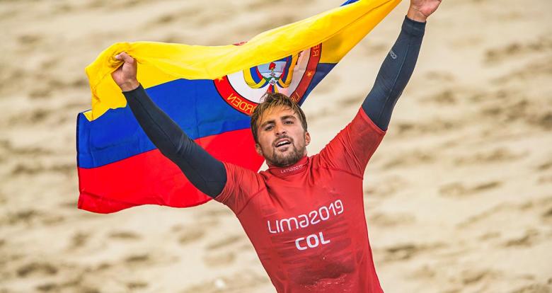 Giorgio Gomez from Colombia holds his flag over his head after his surfing competition at the Lima 2019 Games, in Punta Rocas