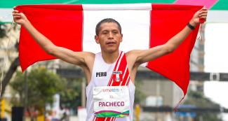 Christian Pacheco holds the Peruvian flag after winning the men’s marathon
