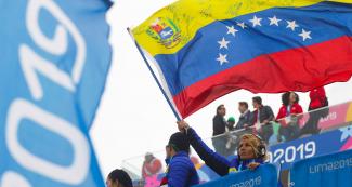 Fanática Venezolana flameando la bandera de su país en competencia de Surf 