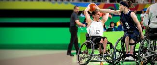 Jugadora de baloncesto en silla de ruedas intentando quitar la pelota de su adversario