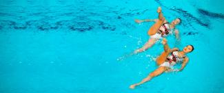 Nadadoras realizando nado sincronizado en competencia de natación artística