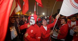 Grupo de peruanos sosteniendo banderas y tocando tambores a manera de celebración