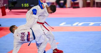 Jovanny Martinez from the Dominican Republic performs a move on Douglas Brose from Brazil in the Lima 2019 Pan American Games karate competition, at the Villa El Salvador Sports Center.