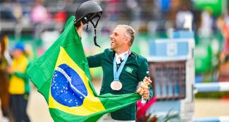 El brasilero, Carlos Parro, celebra tercer puesto en ecuestre con su medalla y bandera de su país en el campo, en los Juegos Lima 2019, en la Escuela de Equitación Lima 2019. 