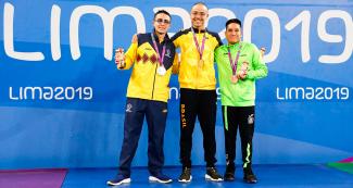 Colombian Gabriel Ortiz (silver), Brazilian Douglas Rocha (gold) and Mexican Andy Guerrero (bronze) posing on the podium in Lima 2019 men’s 100 m backstroke S7 Para swimming competition during medal ceremony at the National Sports Village - VIDENA