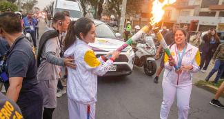 Young torchbearers smile and share the Lima 2019 Parapan American flame. 