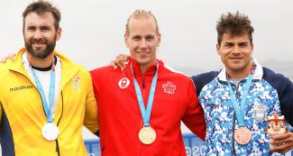 : Canadian Dominik Crete, Ecuadorian César de Cesare, and Argentinian Rubén Rezola smiling while standing at the podium of K1 men 200m event at Lima 2019 