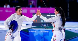 Gabriela Page from Canada and Shia Rodriguez from Mexico high-five each other after fencing competition held at the Lima Convention Center