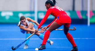 Georgina Petrik from Uruguay and Leticia Fernandez from Cuba aim for the ball in a hockey match at the Lima 2019 Games in Villa Maria del Triunfo.