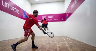 American racquetball player Jacob Bredenbeck hits the ball during the men’s round of 16 against Ramón de León from the Dominican Republic at the Callao Regional Sports Village