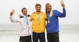Martino Tamil de Perú (plata), Giorgio Gomez de Colombia (oro) y Daniel Hughes de USA (bronce) celebran sus medallas en surf, en los Juegos Lima 2019, realizado en Punta Rocas.