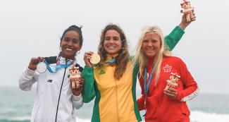 Maria Fernandez de Perú (plata), Chloe Calmon de Brasil (oro) y Mathea Dempfle de Canadá (bronce) celebran sus medallas en surf, ¬en Juegos Lima 2019 en Punta Rocas.