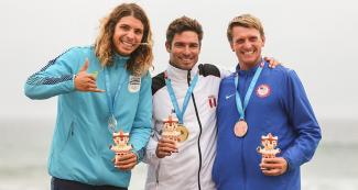 Julian Schweizer from Uruguay (silver), Benoit Clemente from Peru (gold) and Cole Robbins from the USA (bronze) celebrate their medals at the Lima 2019 Games in Punta Rocas