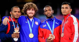 Freestyle wrestling medalists posing on the Lima 2019 podium with their clay cuchimilcos at the Callao Regional Sports Village. 