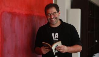 Juan Carlos Fisher sonriendo sosteniendo un libro abierto