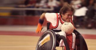 Wheelchair woman struggling to carry rugby ball