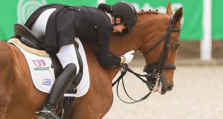 Agustina Bravo de Uruguay sonriente montada a caballo en competencia de ecuestre adiestramiento individual en Lima 2019 en la Escuela de Equitación del Ejército.