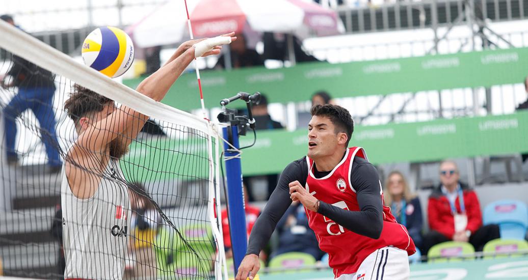 Esteban Grimalt attacks the ball against Canadian Michael Plantinga in the beach volleyball tournament