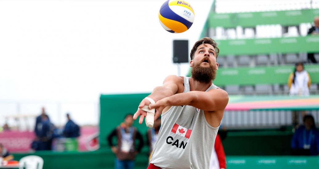 Canadian Michael Plantinga lifts the ball in a beach volleyball match against Chile