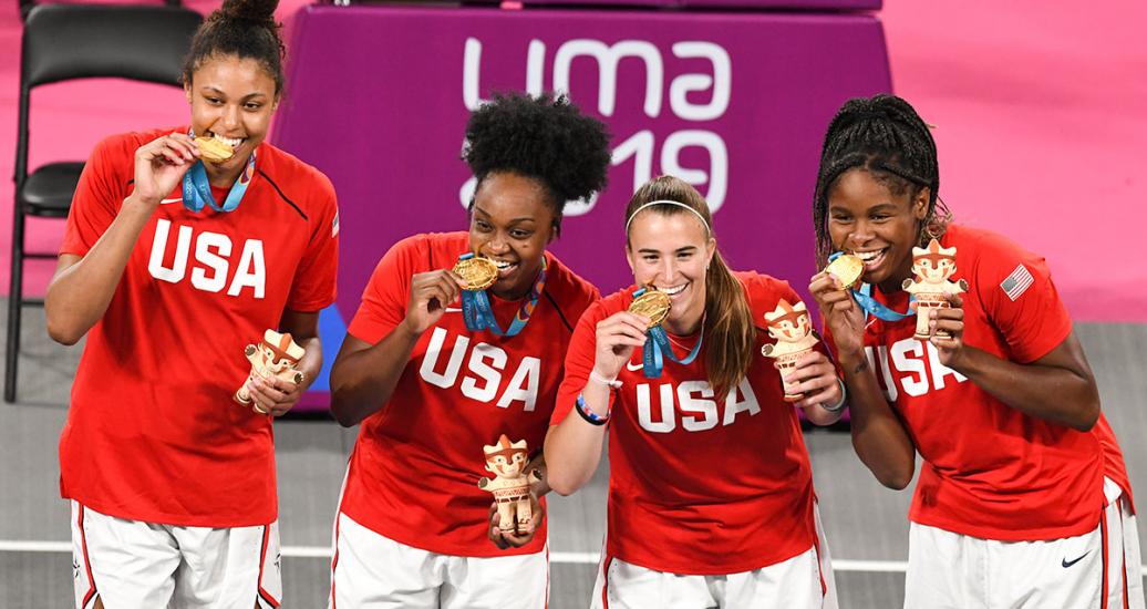 American basketball players Sabrina Ionescu, Olivia Nelson, Ruth Hebard and Christyn Williams bite their gold medals