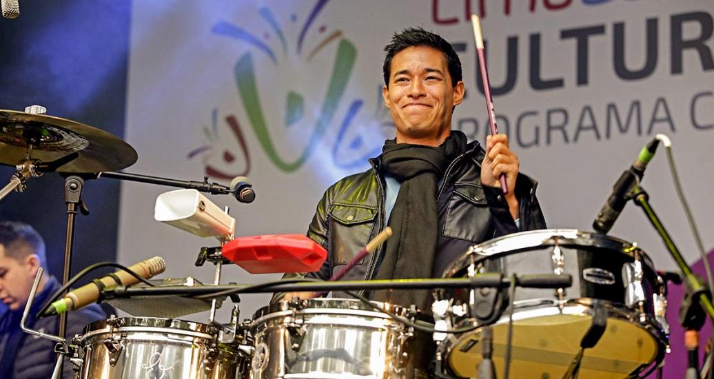 Artista Tony Succar sonriente toca la batería en show musical del Culturaymi del 4 de agosto en Lima 2019
