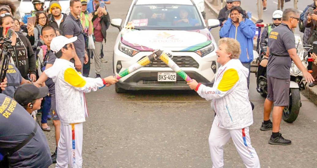 : Torchbearers pass the Lima 2019 Parapan American flame to one another to continue their route. 