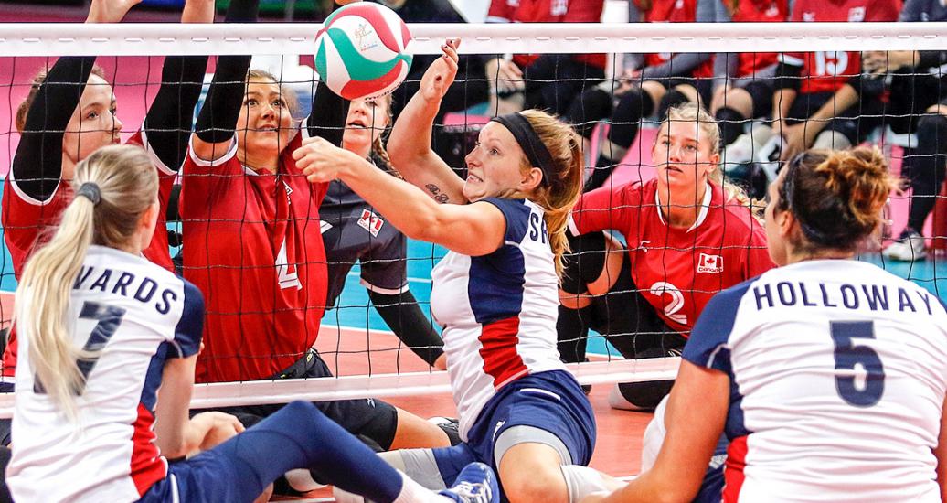 Las Para deportistas de EE. UU. y Canadá se concentran en el balón en un tenso momento del vóleibol sentado en Lima 2019 en la Villa Deportiva Regional del Callao