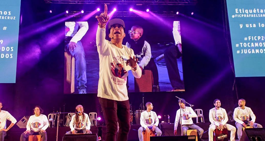 Presentador sobre el escenario frente a artistas con cajones como parte del Festival Internacional de Cajón y Percusión Rafael Santa Cruz en el Culturaymi el día 3 de agosto en Lima 2019