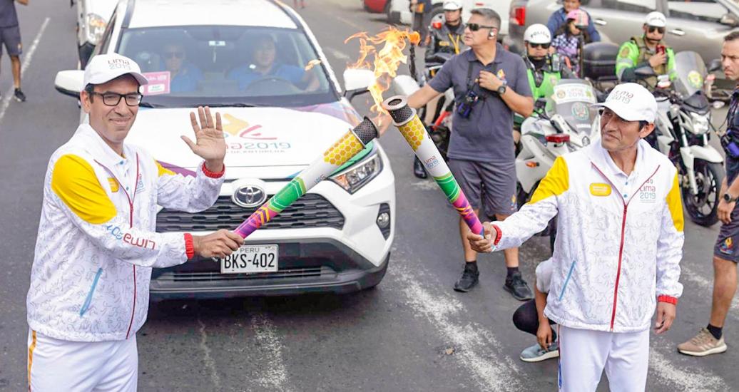 Torchbearer waves to the camera while he passes the Lima 2019 Parapan American flame