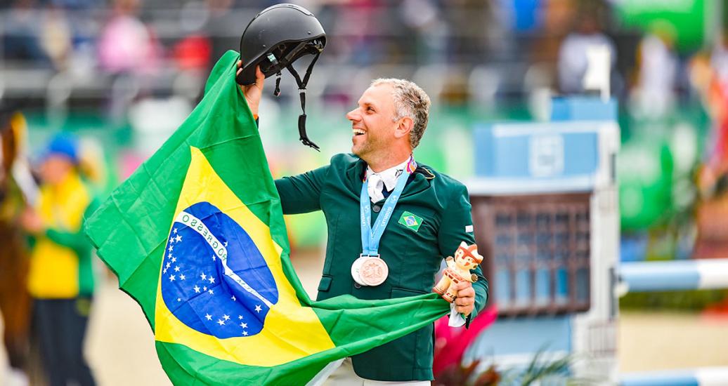 El brasilero, Carlos Parro, celebra tercer puesto en ecuestre con su medalla y bandera de su país en el campo, en los Juegos Lima 2019, en la Escuela de Equitación Lima 2019. 