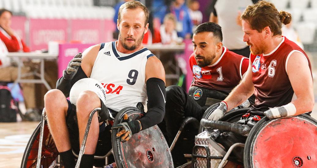 Eric Newby (USA) llevando el balón entre sus piernas mientras se enfrenta a dos jugadores chilenos durante partido de rugby en silla de ruedas en los Juegos Parapanamericanos Lima 2019. 