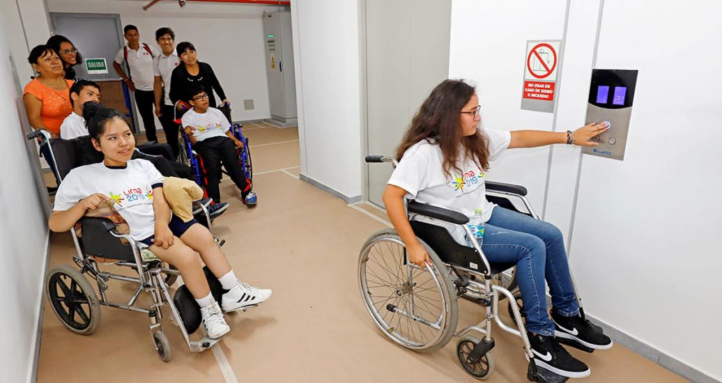 Grupo de Para atletas en silla de ruedas y sus acompañantes llamando al ascensor en una torre de la Villa Panamericana Lima 2019