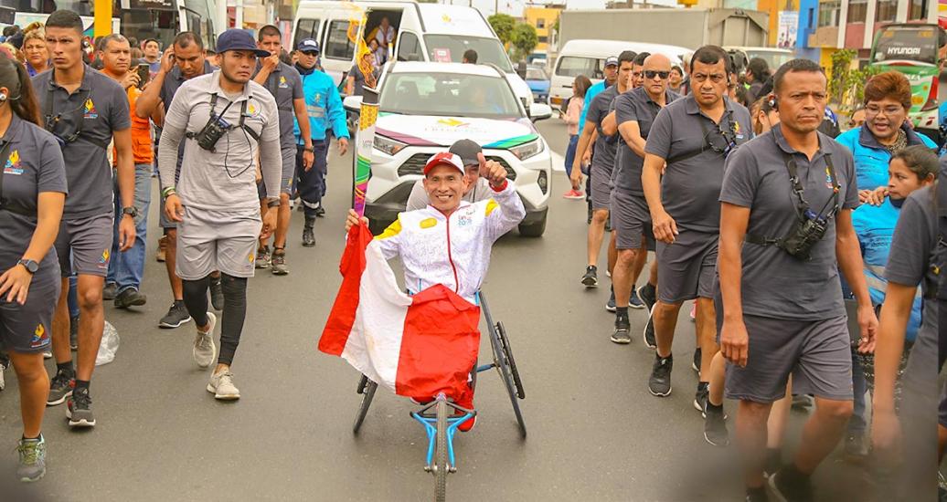 Un hombre lleva la antorcha parapanamericana en el aire y una bandera del Perú en el regazo en el tercer día del Relevo de la Antorcha Parapanamericana de Lima 2019
