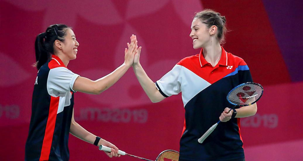 Rachel Honderich and Kristen Tsai from Canada share a smile and join hands in a badminton doubles event against Brazil held at the National Sports Village – VIDENA at the Lima 2019 Pan American Games