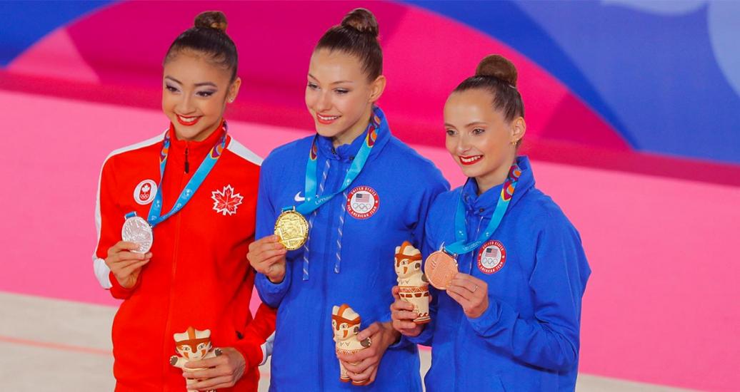 Katherine Uchida de Canadá (plata) y Evita Griskenas y Camila Feeley de USA, oro y bronce respectivamente, sonríen con sus medallas de gimnasia rítmica, en los Juegos Lima 2019, en el Polideportivo Villa El Salvador