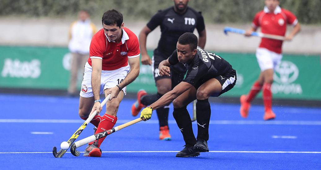 : The Chilean Sven Richter and Caleb Guiseppi from Trinidad and Tobago competing for the ball in the Lima 2019 hockey event held at the Villa María del Triunfo Sports Center